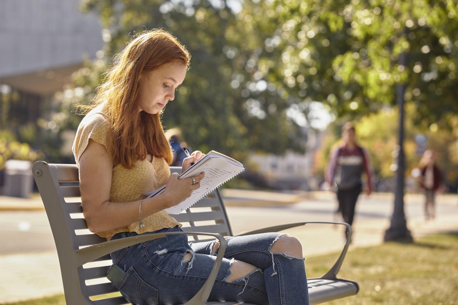 一位<a href='http://ikny.ngskmc-eis.net'>全球十大赌钱排行app</a>学院的学生在校园里的长椅上读书.